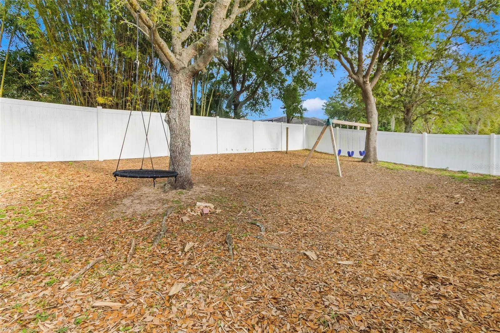 fenced in backyard with trees and white fence
